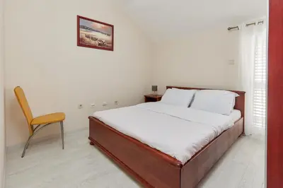 a bedroom with a bed and a chair in it at Apartment Mrsulja in Kotor