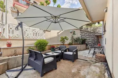 a patio with chairs and an umbrella at Apartment Mrsulja in Kotor