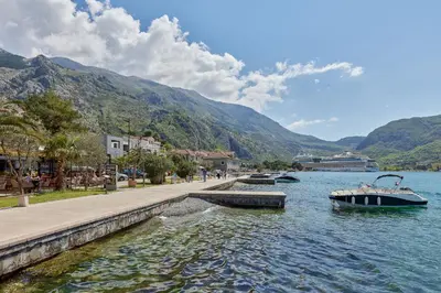 a boat in a body of water with mountains at Apartment Mrsulja in Kotor