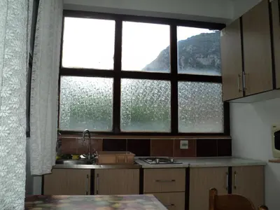 a kitchen with two windows and a sink and a table at Apartments Škaljari in Kotor