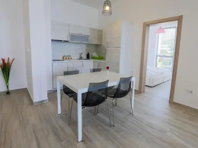 a kitchen and dining room with a white table and chairs at Apart Hotel Sea Fort in Sutomore