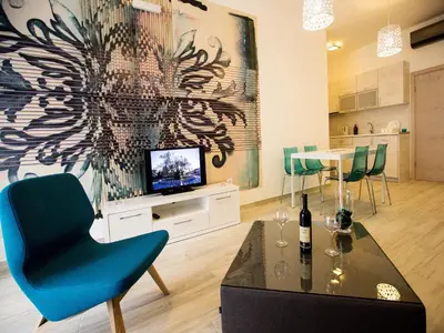 a living room with a blue chair and a television at Apart Hotel Sea Fort in Sutomore
