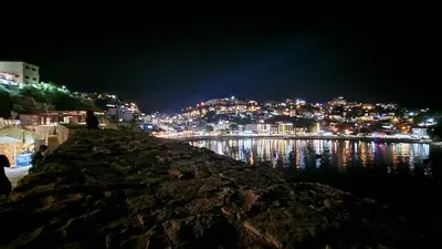 a view of a city at night from the water at Marelis condo with sea view in Ulcinj