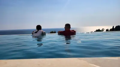 a man and a woman sitting in a swimming pool at Marelis condo with sea view in Ulcinj