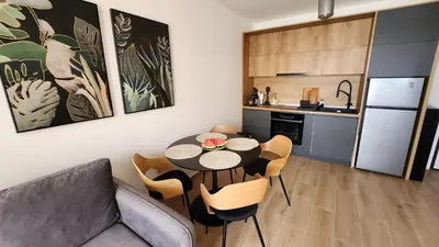 a living room with a table and chairs and a kitchen at Marelis condo with sea view in Ulcinj
