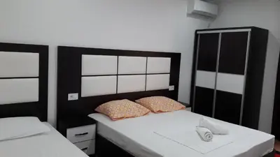 a bedroom with two beds with white sheets and a black headboard at Apartments Sija in Ulcinj