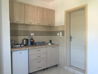a kitchen with wooden cabinets and a sink and a door at Apartments Nurkovic in Dobra Voda