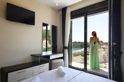 a woman in a green dress is looking out the window at Shine residence in Budva