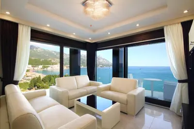 a living room with white furniture and large windows at Shine residence in Budva