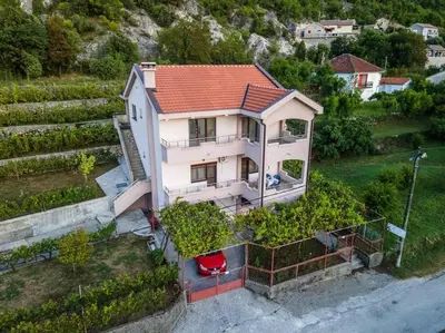 a white house with a red roof on a hill at Pavle's Oasis in Virpazar