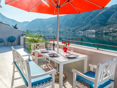 a table and chairs on a balcony with an umbrella at Apartments Windrose in Kotor