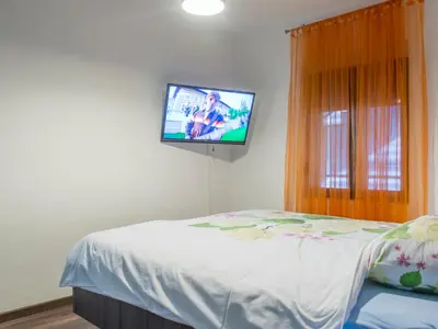 a bedroom with a bed with a tv on the wall at Apartments Windrose in Kotor