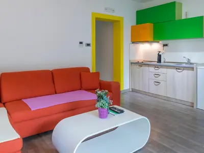 a living room with a red couch and a kitchen at Apartments Windrose in Kotor