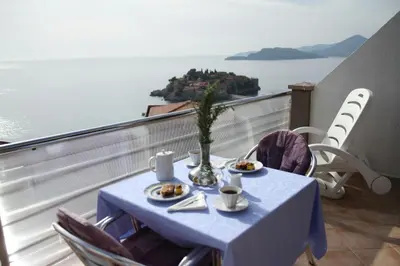 a table with plates of food on top of a balcony at Apartments Grloman in Sveti Stefan