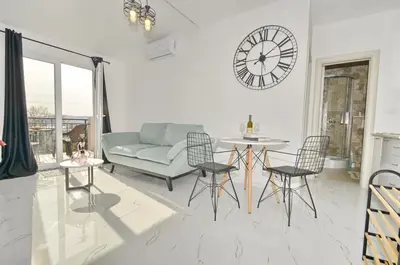 a living room with a couch and a clock on the wall at KM Apartments in Kotor