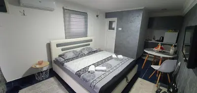 a small bedroom with a bed and a small kitchen at Cozzy apartment near the Aiport Podgorica in Mitrovići