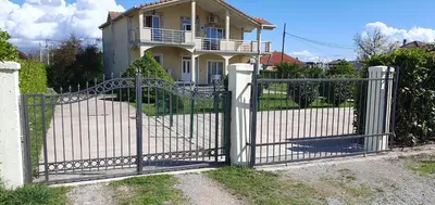 a white gate in front of a house at Cozzy apartment near the Aiport Podgorica in Mitrovići