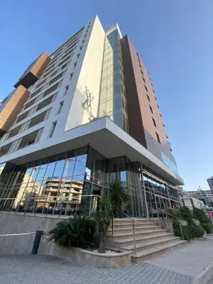 a tall building with glass windows and palm trees in front at Seabreeze apartments Budva in Budva