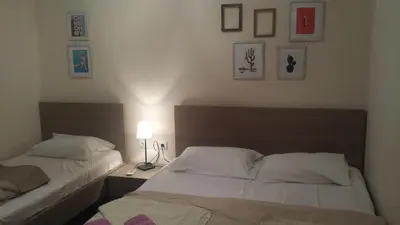 two beds in a bedroom with two lamps and pictures on the wall at Apartments Fortunella in Budva