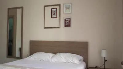 a bedroom with a bed with white pillows and pictures on the wall at Apartments Fortunella in Budva