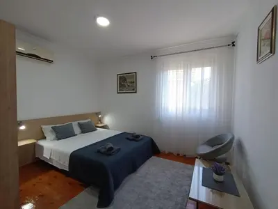a bedroom with a bed with a blue blanket and a window at Entire house floor - 2-Bedroom Cozy & Peaceful Apartment in Podgorica