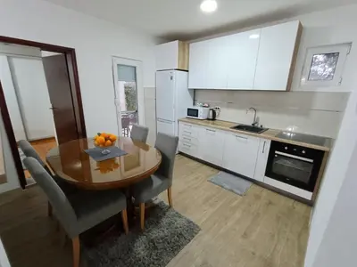 a kitchen with a wooden table and a kitchen with white cabinets at Entire house floor - 2-Bedroom Cozy & Peaceful Apartment in Podgorica