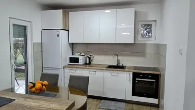 a kitchen with white cabinets and a table with oranges on it at Entire house floor - 2-Bedroom Cozy & Peaceful Apartment in Podgorica