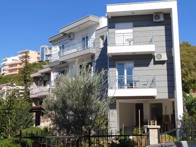 an apartment building with balconies and a tree at Family House Milic in Ulcinj in Ulcinj