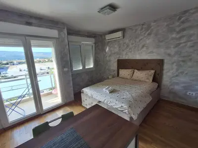 a bedroom with a bed and a table and windows at Apartman City Kvart Podgorica in Podgorica