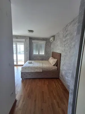 a bedroom with a bed in a room with wooden floors at Apartman City Kvart Podgorica in Podgorica