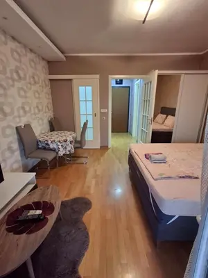 a bedroom with a bed and a table and a couch at Apartman City Kvart Podgorica in Podgorica