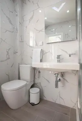 a white bathroom with a toilet and a sink at Pržno Bay in Sveti Stefan