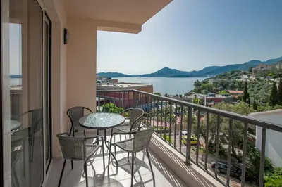 a balcony with a table and chairs and a view of the water at Pržno Bay in Sveti Stefan