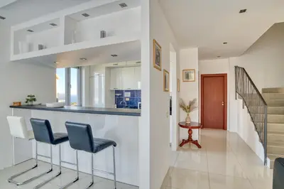 a kitchen and living room with a bar with stools at Villa Azure Krimovica Kotor in Krimovice