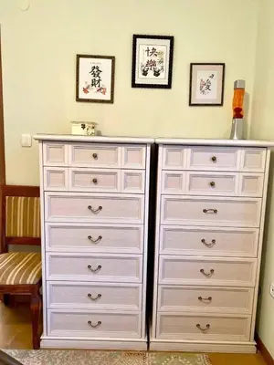 a white dresser in a bedroom with two pictures on the wall at Orhid apartment Becici one in Budva