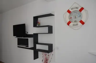 a living room with a tv and a clock on the wall at Studios Seaview in Dobra Voda