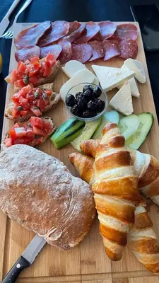 a cutting board with different types of bread and meats at Apartments Contessa in Ulcinj