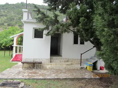 a white house with a door in a yard at Holiday Home Idyllic Cottage in Čanj