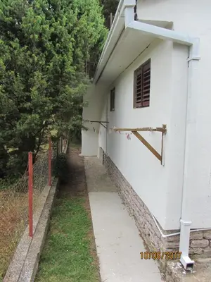 a white building with a fence next to a sidewalk at Holiday Home Idyllic Cottage in Čanj