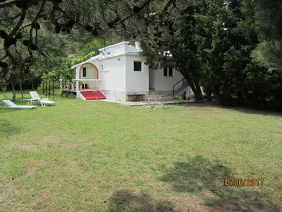 a small white house in a field with a yard at Holiday Home Idyllic Cottage in Čanj