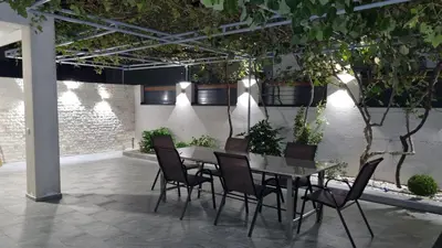a table and chairs in a patio with plants at Apartmani Sutomore Tri Palme in Sutomore