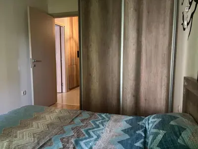 a bedroom with a bed and a wooden door at NADJA Apartman City Kvart in Kruševac