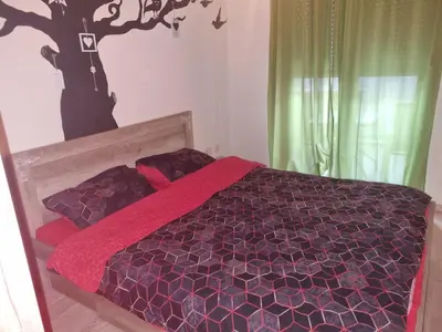 a bedroom with a bed with a tree on the wall at NADJA Apartman City Kvart in Kruševac