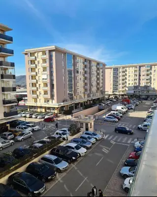 a parking lot with parked cars and large buildings at NADJA Apartman City Kvart in Kruševac