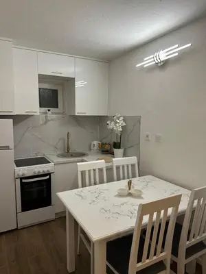a kitchen with a white table and chairs and a white table and chairsktop at Budva apartman Centar in Budva
