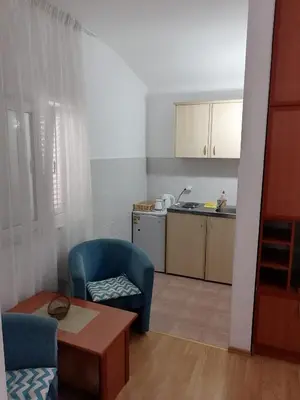 a small kitchen with a blue chair and a table at Guest House Garden in Budva