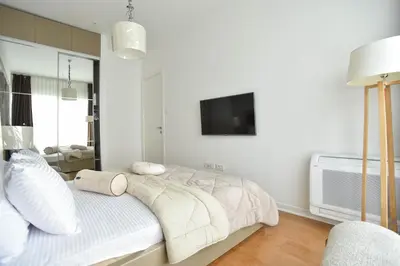 a white bedroom with a bed and a tv at Apartment with 2 rooms in Tre canne hotel in Budva