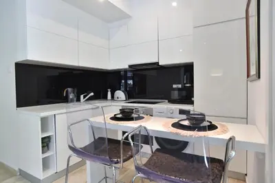 a kitchen with white cabinets and a table with chairs at Luxury one bedroom apartment in beachfront apart Hotel in Budva