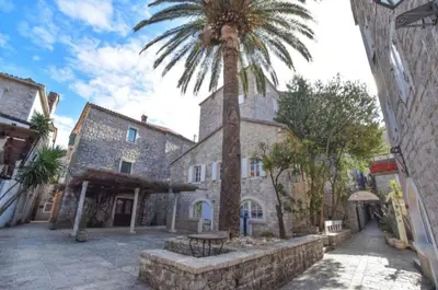 a palm tree in front of a building with a table at OLD TOWN Budva apart 3 with balcony in Budva