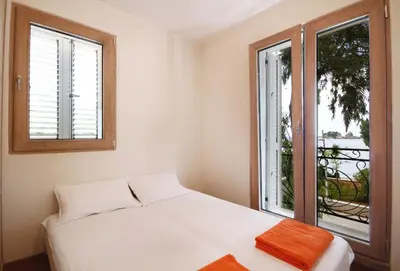 a bedroom with a white bed and two windows at Apartments Dangubic in Petrovac na Moru